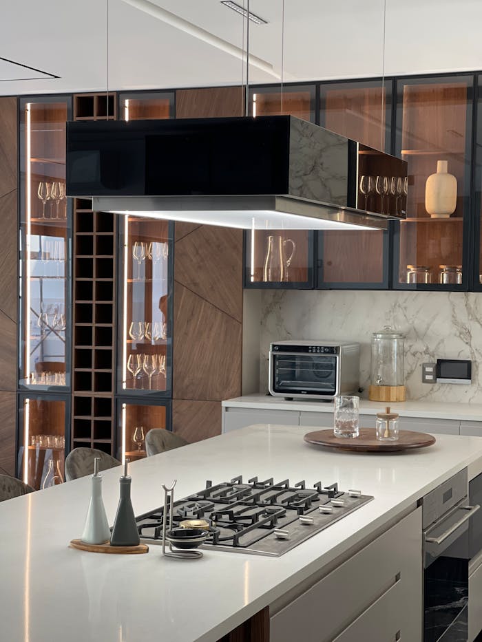 about-01 Sleek kitchen design featuring a gas cooktop, glass cabinets, and stylish ventilation hood.