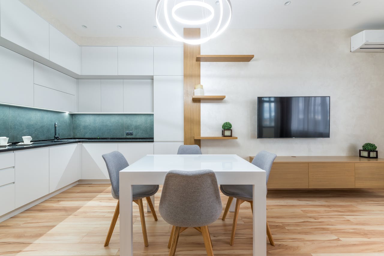service-02 Modern flat interior with table with chairs next to shelves and TV on wall near open kitchen with cupboards